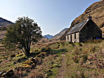 Old house amidst trees and mountains against sky