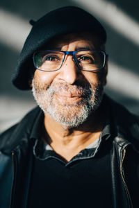 Portrait of smiling senior man with eyeglasses against wall