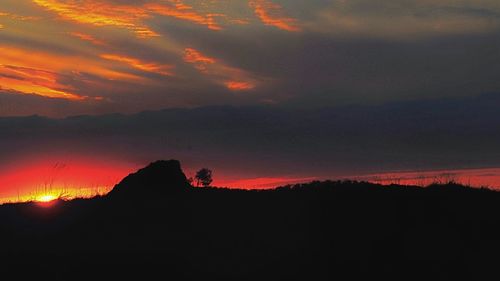 Scenic view of silhouette mountains against orange sky