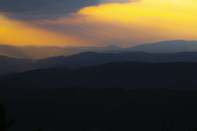 Scenic view of silhouette mountains against orange sky