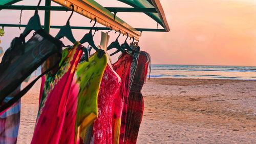 Multi colored umbrellas hanging on beach against sky during sunset