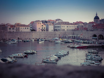 Boats moored in city against clear sky