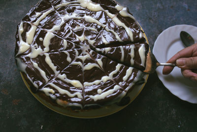 Cropped hand of person holding chocolate cake on table