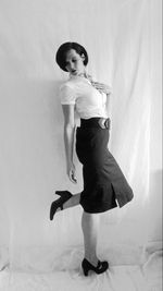 Portrait of young woman standing against white background