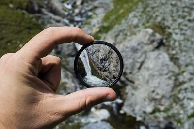 Hand holding glass in front of waterfall