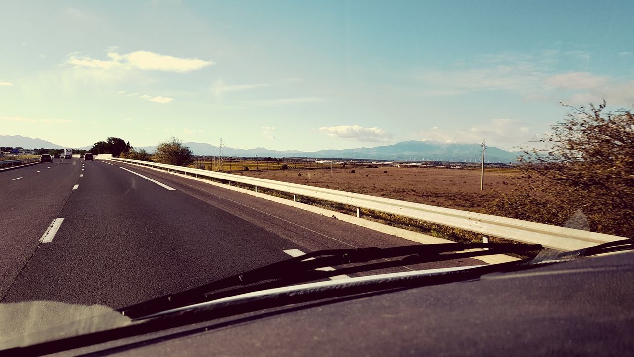 ROAD AGAINST SKY SEEN THROUGH CAR WINDSHIELD