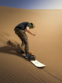 Low section of man skateboarding on sand