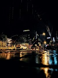 Illuminated bridge by buildings in city at night