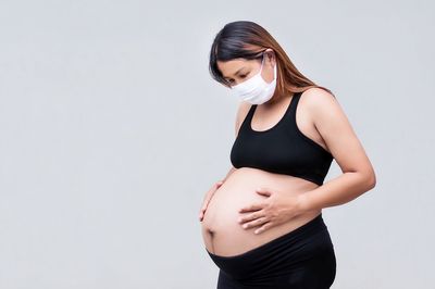 Beautiful young woman standing against white background
