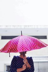 Rear view of woman with umbrella against sky