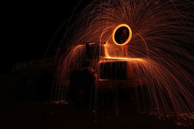 Man spinning wire wool while standing on vehicle at night