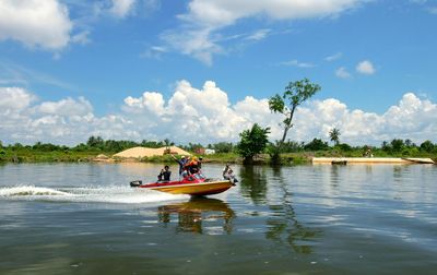 People in boat on river against sky