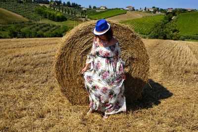 Mid adult woman standing by hay bale on field