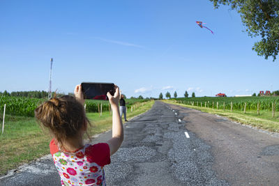 Rear view of woman photographing on road