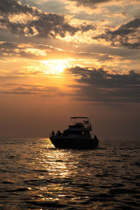 Boat sailing on sea against sky during sunset
