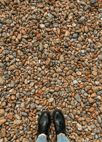 Low section of man standing on pebbles