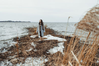 Woman standing on beach against sky