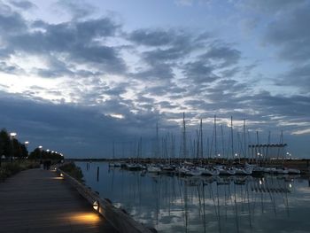 Boats in harbor against cloudy sky