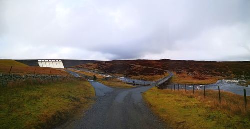 Road amidst field against sky