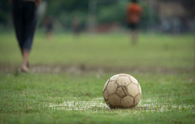 Close-up of soccer ball on field with people in background