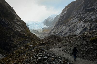 Rear view of woman walking on mountain against sky