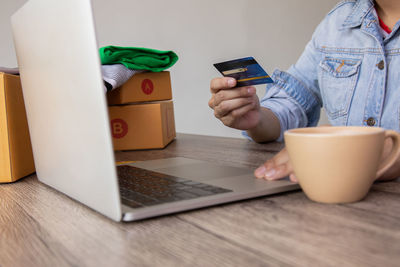 Midsection of man using mobile phone while sitting on table