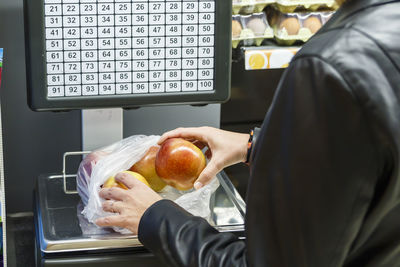 Midsection of person weighing apples on scale