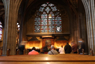 Rear view of people walking and sitting in church