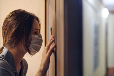 Close-up of woman wearing mask looking through peephole