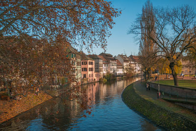 River amidst buildings against sky during autumn