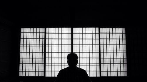 Silhouette of man against window