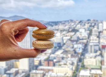 Midsection of person holding ice cream against buildings in city