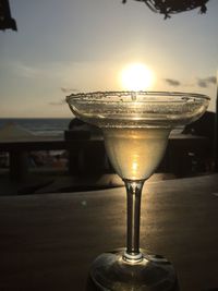 Close-up of beer glass on table against sky during sunset