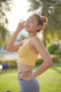 Young woman closed eyes while standing outdoors at sunset.