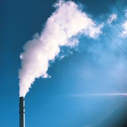 Low angle view of smoke emitting from chimney against sky