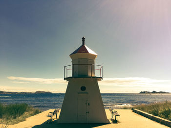 Lighthouse by sea against sky during sunset