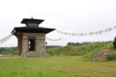 Low angle view of prayer flags hanging on temple against clear sky