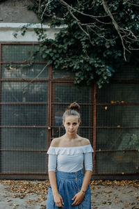 Portrait of young woman standing against tree