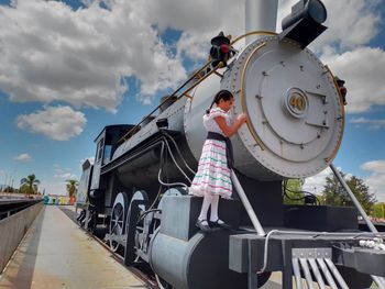 Low angle view of woman standing on train against sky