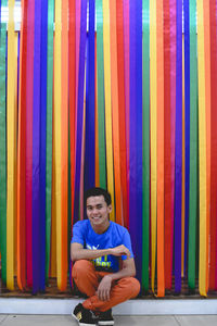 Portrait of young man standing against multi colored wall