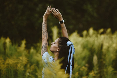 Rear view of woman with arms raised standing outdoors