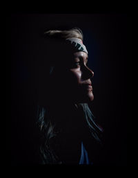 Close-up of woman against black background