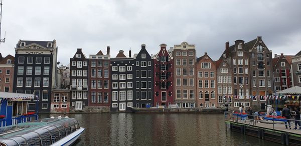 Buildings by canal against sky in city