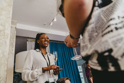 Low angle view of smiling businesswoman holding drink glass during event at convention center