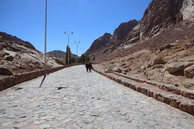 Rear view of people walking on mountain against clear sky