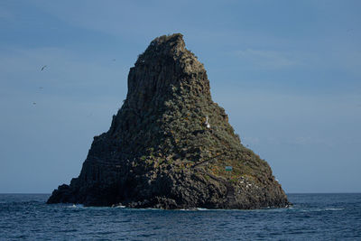 Rock formation in sea against sky
