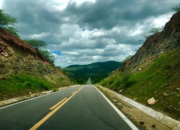 Road leading towards mountains against sky