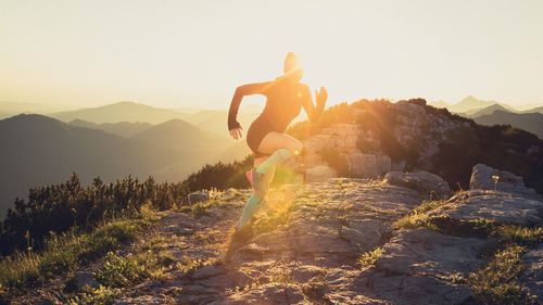 Woman running on mountain peak during sunrise