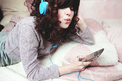 Woman listening music while lying on bed at home