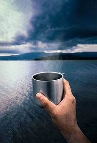 Close-up of hand holding steaming coffee cup